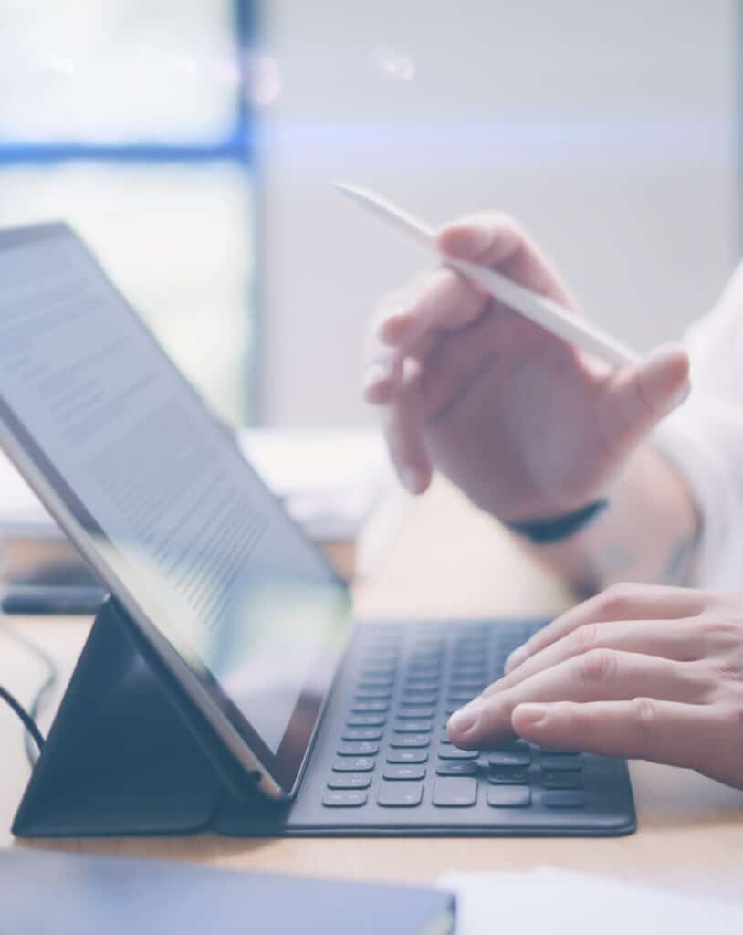 Travail sur tablette avec clavier et stylet Mains tapant sur un clavier d'accessoire de tablette, tenant un stylet pour réviser un document affiché.